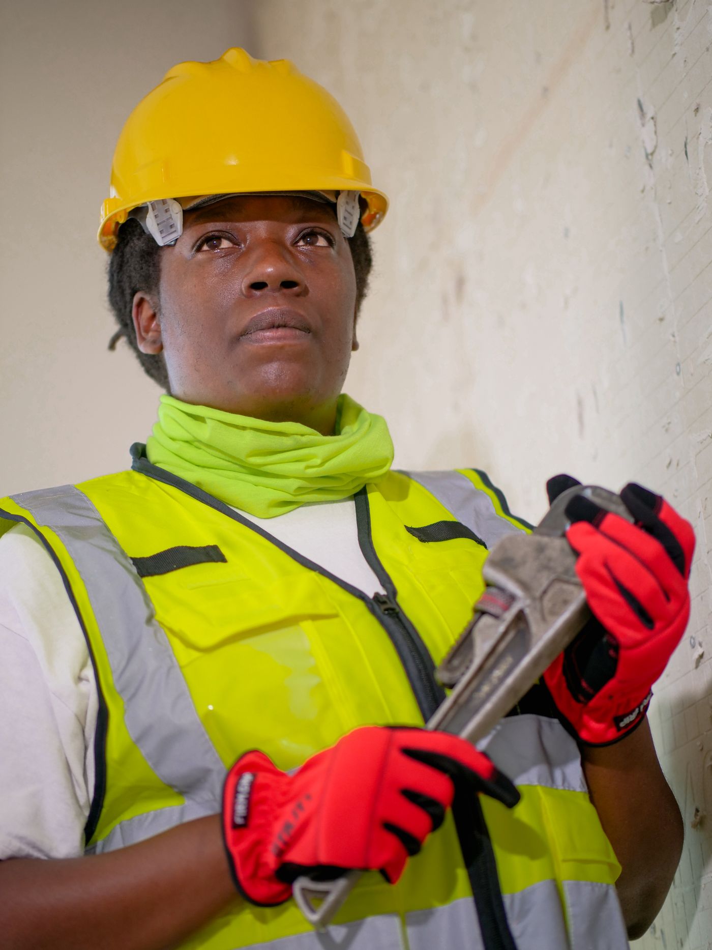 Professional plumber in protective gear holding a pipe wrench